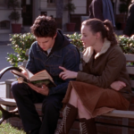 Gilmore Girls still: Rory and Jess sitting on a bench looking at a book
