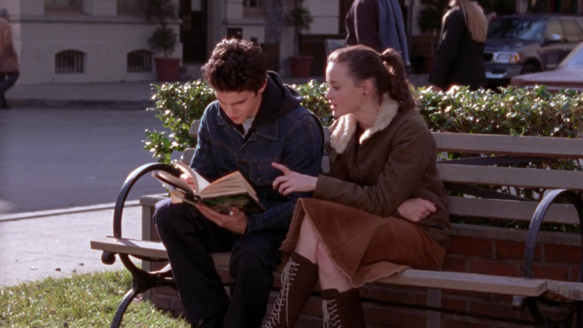 Gilmore Girls still: Rory and Jess sitting on a bench looking at a book