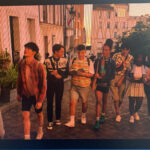 Screencap of the Heartstopper Paris squad walking up the street in a line
