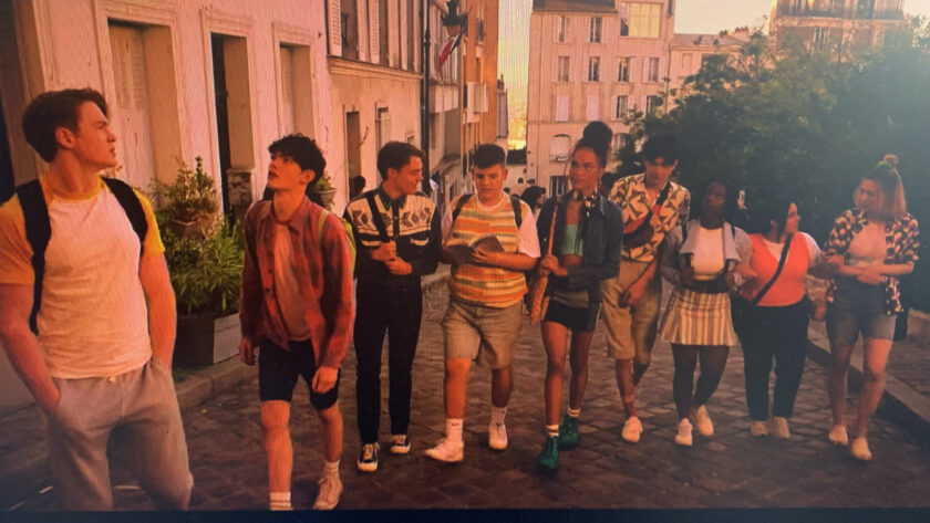 Screencap of the Heartstopper Paris squad walking up the street in a line